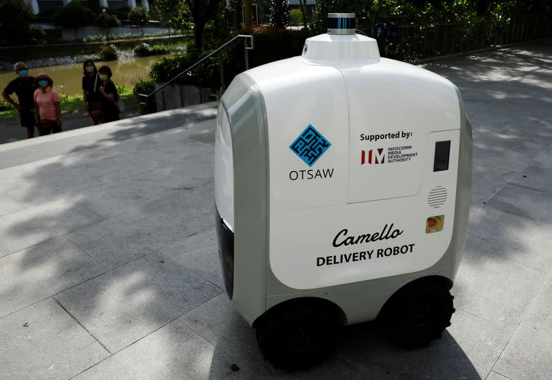 People look on as Carmello, an autonomous grocery delivery robot, makes its way during a delivery in Singapore