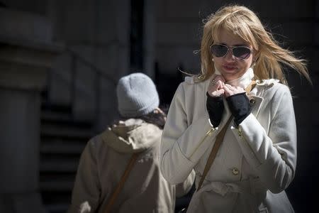 People walk through the wind and cold on Wall Street in New York's financial district March 19, 2015. REUTERS/Brendan McDermid