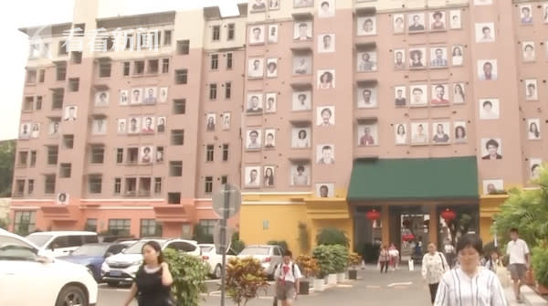 中國大陸1棟大樓在外牆懸掛上百幅張口微笑的人臉大頭照，讓附近居民直呼「簡直像來到了墓地」！（圖片翻攝看看新聞）