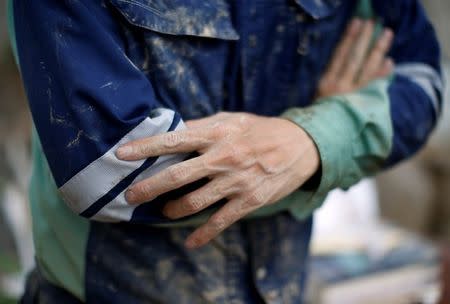 Muddy hands of 51-year-old Kairyu Takahashi, an Okayams prefectural assemblyman, are seen as he tries to remove mud and debris from his house in a flood affected area in Mabi town in Kurashiki, Okayama Prefecture, Japan, July 12, 2018. Picture taken July 12, 2018. REUTERS/Issei Kato