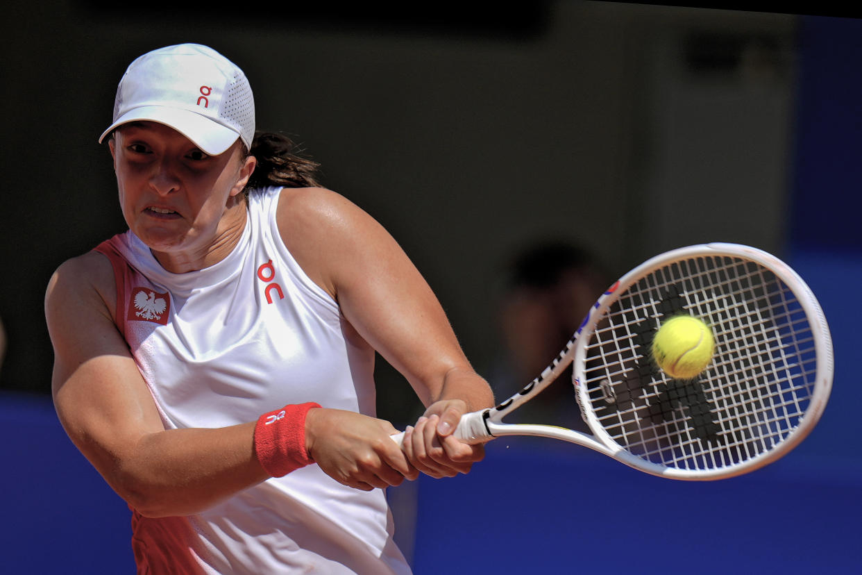 Iga Swiatek of Poland hits a backhand shot to Diane Parry of France during the women's singles tennis competition, at the 2024 Summer Olympics, Monday, July 29, 2024, in Paris, France. (AP Photo/Andy Wong)