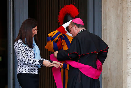 A woman helps a bishop to adjust his belt before entering the synod hall to take part at the afternoon session led by Pope Francis at the Vatican October 16, 2018. Picture taken October 16, 2018. REUTERS/Max Rossi