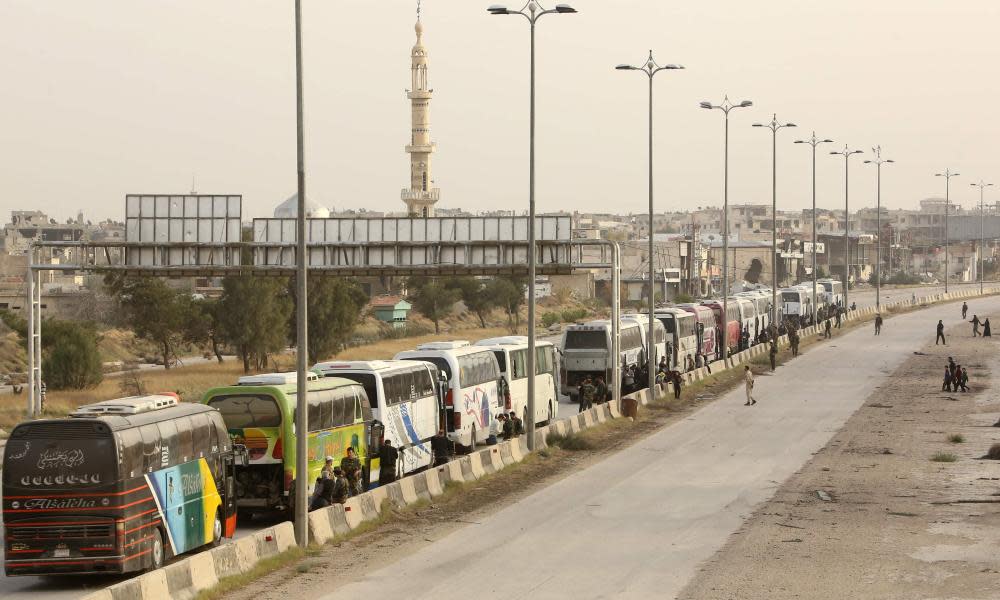 Syrian rebel fighters from the Ahrar al-Sham faction wait by buses