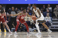 West Virginia guard Taz Sherman (12) passes while defended by Oklahoma guard Elijah Harkless (55) during the first half of an NCAA college basketball game in Morgantown, W.Va., Wednesday, Jan. 26, 2022. (AP Photo/Kathleen Batten)