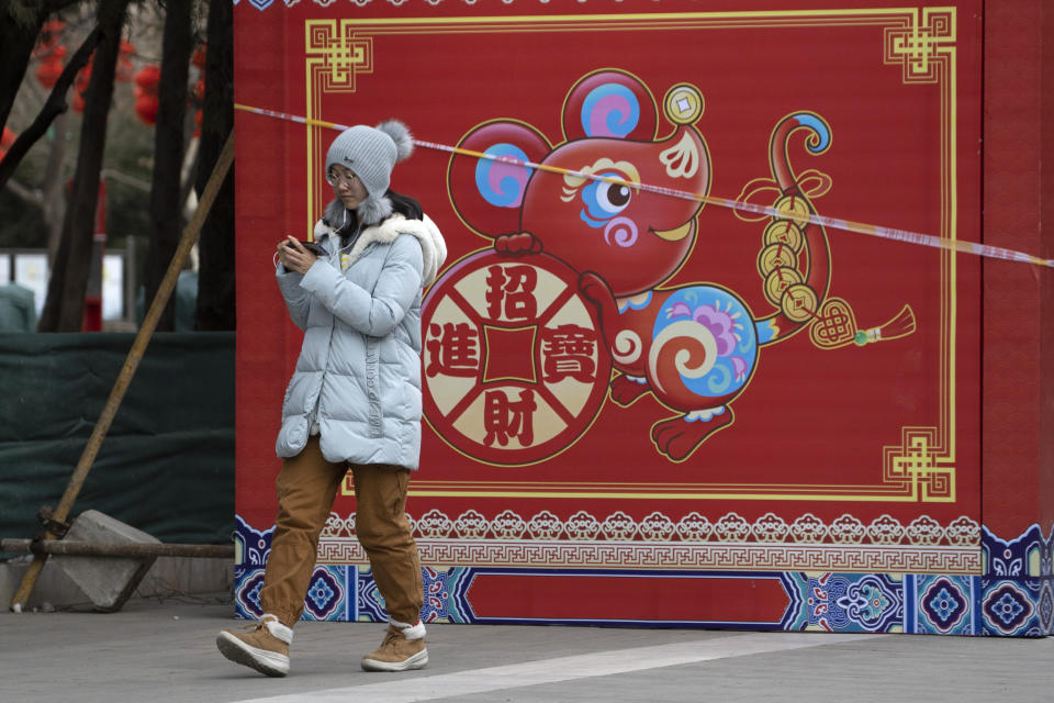 A woman walks a depiction of a Rat with the words "Bring in wealth and treasures" ahead of the Chinese Lunar New Year Year of the Rat celebrations in Beijing on Thursday, Jan. 16, 2020. China's government welcomed an interim trade deal with Washington and said Thursday the two sides need to address each other's "core concerns." (AP Photo/Ng Han Guan)