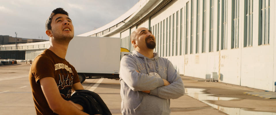 Zwei Flüchtlinge betrachten das Gebäude des ehemaligen Flughafen Tempelhof von außen. (Bild: Filmstill/ ddp images)