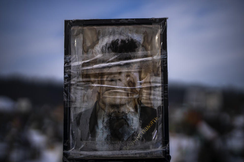 A worn-out portrait of Ivan Tychynskyi Petrovych, 82, sits on his grave at a cemetery in Irpin, Ukraine, on the outskirts of Kyiv, on Thursday, Feb. 9, 2023. He was buried on June 6, 2022. (AP Photo/Emilio Morenatti)