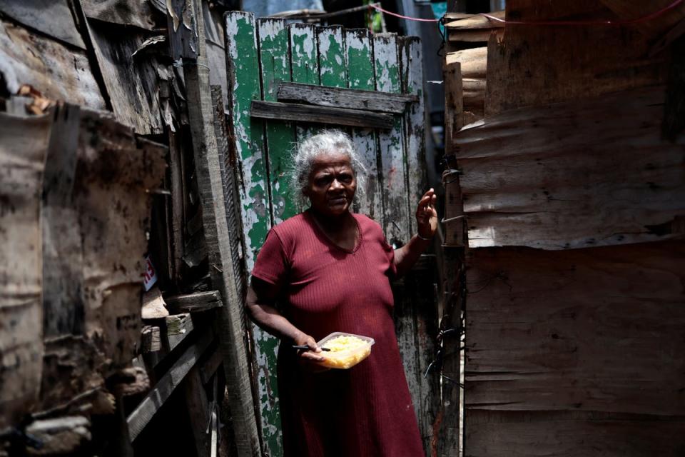 Maria Jose holds her lunch, a bowl of rice, in front of her house in the Arco Iris favela (Reuters)