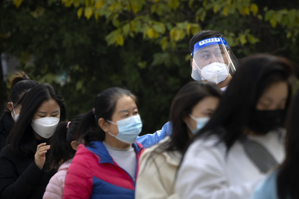 A worker wearing a face shield talks to people as they stand in line for COVID-19 tests at a coronavirus testing site in Beijing, Thursday, Nov. 10, 2022. A surge in COVID-19 cases has spurred lockdowns in the southern Chinese manufacturing hub of Guangzhou, adding to financial pressure that has disrupted global supply chains and sharply slowed growth in the world's second-largest economy. (AP Photo/Mark Schiefelbein)