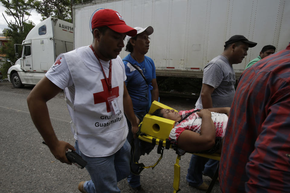 A faint Honduran migrant woman is helped by Guatemalan Red Cross workers while a caravan of Hondurans migrants are blocked at the border with Honduras that connects with Agua Caliente, Guatemala, Monday, Oct. 15, 2018. Hundreds of Honduran migrants were eventually allowed to cross at the Guatemalan border under a broiling sun Monday hoping to make it to new lives in the United States, far from the poverty and violence of their home nation. (AP Photo/Moises Castillo)