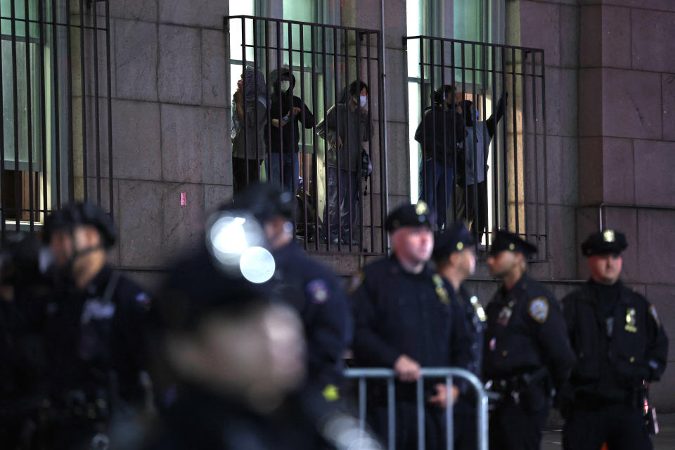 Los estudiantes miran desde una ventana mientras los agentes de la policía de Nueva York hacen guardia frente a la Universidad de Columbia en la ciudad de Nueva York el 30 de abril de 2024 / Foto: AFP