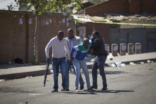 South African police officers detained looters after the outbreak of rioting in the Johannesburg township of Alexandra