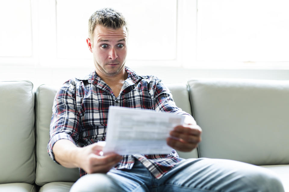 A Shocked man holding some documents in the livingroom