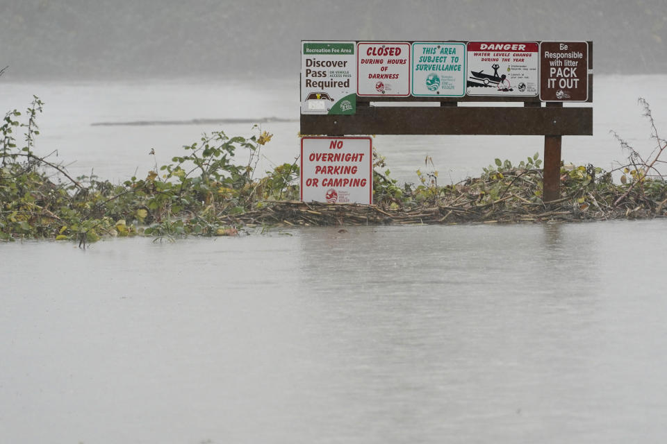 Recreation signs are shown near rising water from the Snoqualmie River, Friday, Nov. 12, 2021, as rain falls near Fall City, Wash. Forecasters said the storms are being caused by an atmospheric river, known as the Pineapple Express and rain was expected to remain heavy in Oregon and Washington through Friday night. (AP Photo/Ted S. Warren)