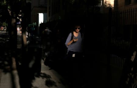 A woman uses her mobile phone as she walks on a street in Buenos Aires, Argentina, March 15, 2018. Picture taken March 15, 2018. REUTERS/Marcos Brindicci