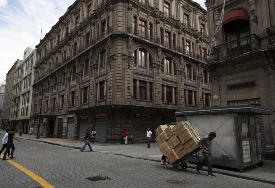 Un hombre tira de una carretilla con mercancía cerca de un edificio cerrado en el centro de la Ciudad de México, el martes 28 de julio de 2020. Con el país enfrentando una profunda recesión económica, el presidente mexicano Andrés Manuel López Obrador ha presionado por reabrir la economía rápidamente aun cuando las infecciones y muertes por COVID-19 continúan aumentando. (Foto AP/Fernando Llano)