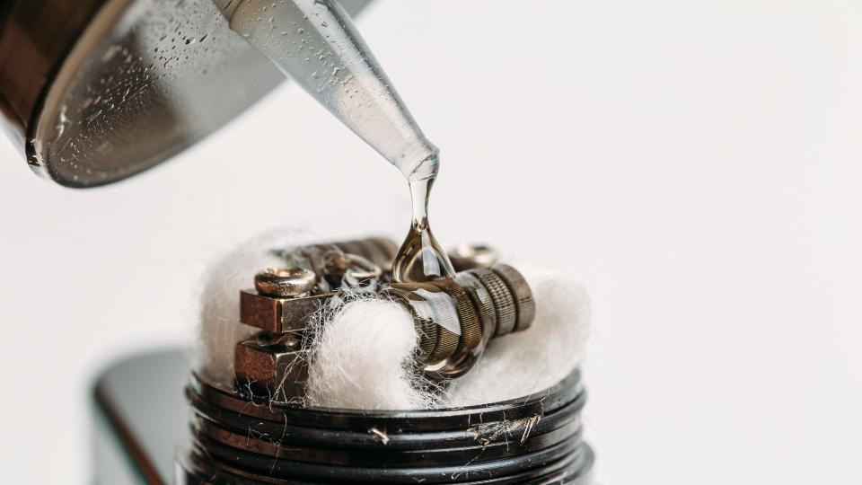 Close up of e-liquid being dropped onto coil of an e-cigarette.