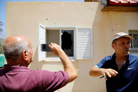 A man takes a photo of a window damaged by a rocket fired from the Gaza Strip that landed near it, in a Kibbutz on the Israeli side of the Israeli-Gaza border, June 20, 2018. REUTERS/Amir Cohen