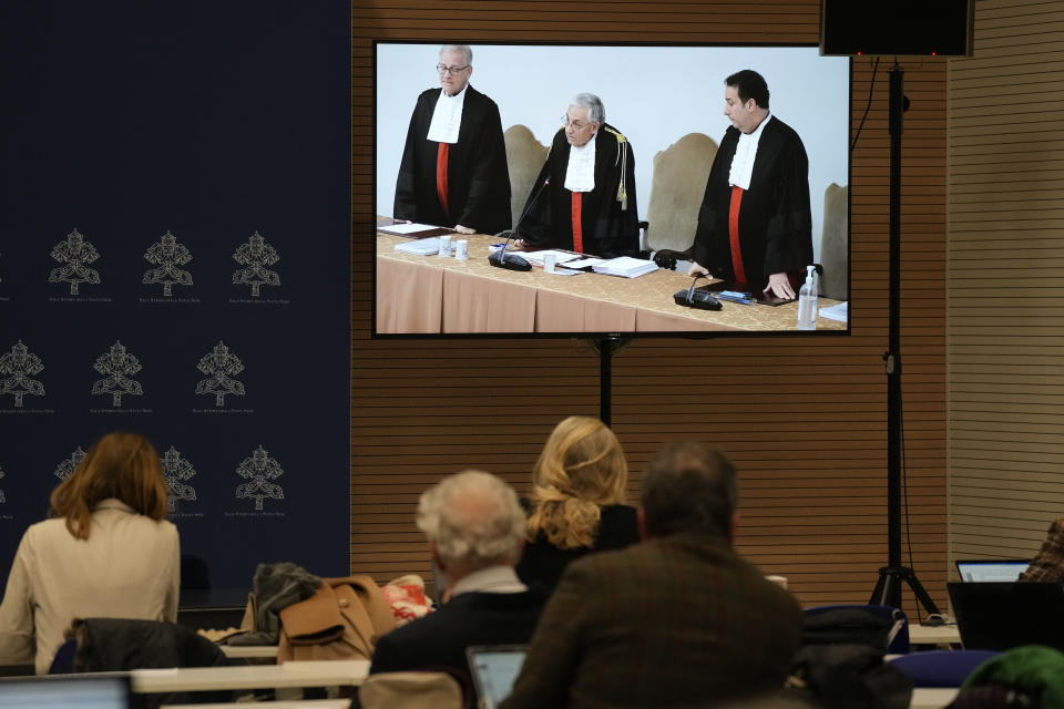 Reporters watch a screen showing Vatican tribunal president Giuseppe Pignatone reading the verdict of a trial against Cardinal Angelo Becciu and nine other defendants, in the Vatican press room, Saturday, Dec. 16, 2023. A once-powerful cardinal and nine other people are to learn their fates when a Vatican tribunal hands down verdicts in a complicated financial trial that has aired the tiny city state's dirty laundry. Judge Giuseppe Pignatone will read out the verdicts of the three-judge panel in the converted courtroom in the Vatican Museums on Saturday. (AP Photo/Andrew Medichini)