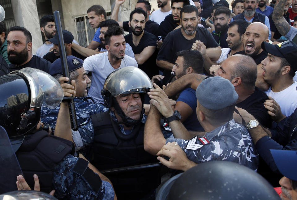 Hezbollah supporters clash with Lebanese riot policemen during a protest in Beirut, Lebanon, Tuesday, Oct. 29, 2019. Beirut residents have scuffled with Lebanese protesters blocking a main thoroughfare, prompting riot police to move to separate them. The tension Tuesday comes on the 13th day of anti-government protests. (AP Photo/Bilal Hussein)