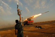 <p>A rebel fighter celebrates as his comrades fire a rocket barrage toward the positions of troops loyal to Libyan ruler Muammar Gaddafi April 14, 2011 west of Ajdabiyah, Libya. Rebels exchanged artillery and rocket fire with loyalist troops west of Ajdabiyah April 14 as the confict engulfing Libya continued. (Photo by Chris Hondros/Getty Images) </p>