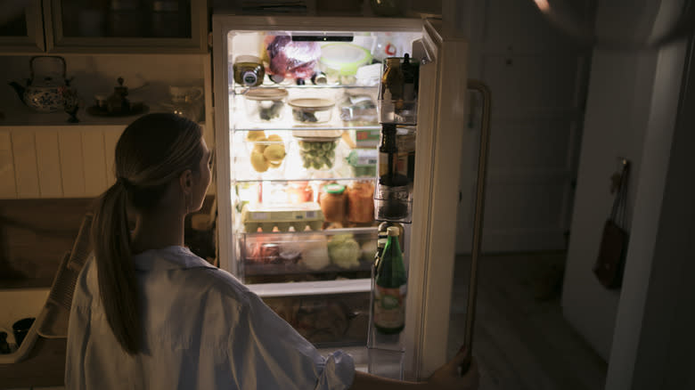 woman looking in open refrigerator