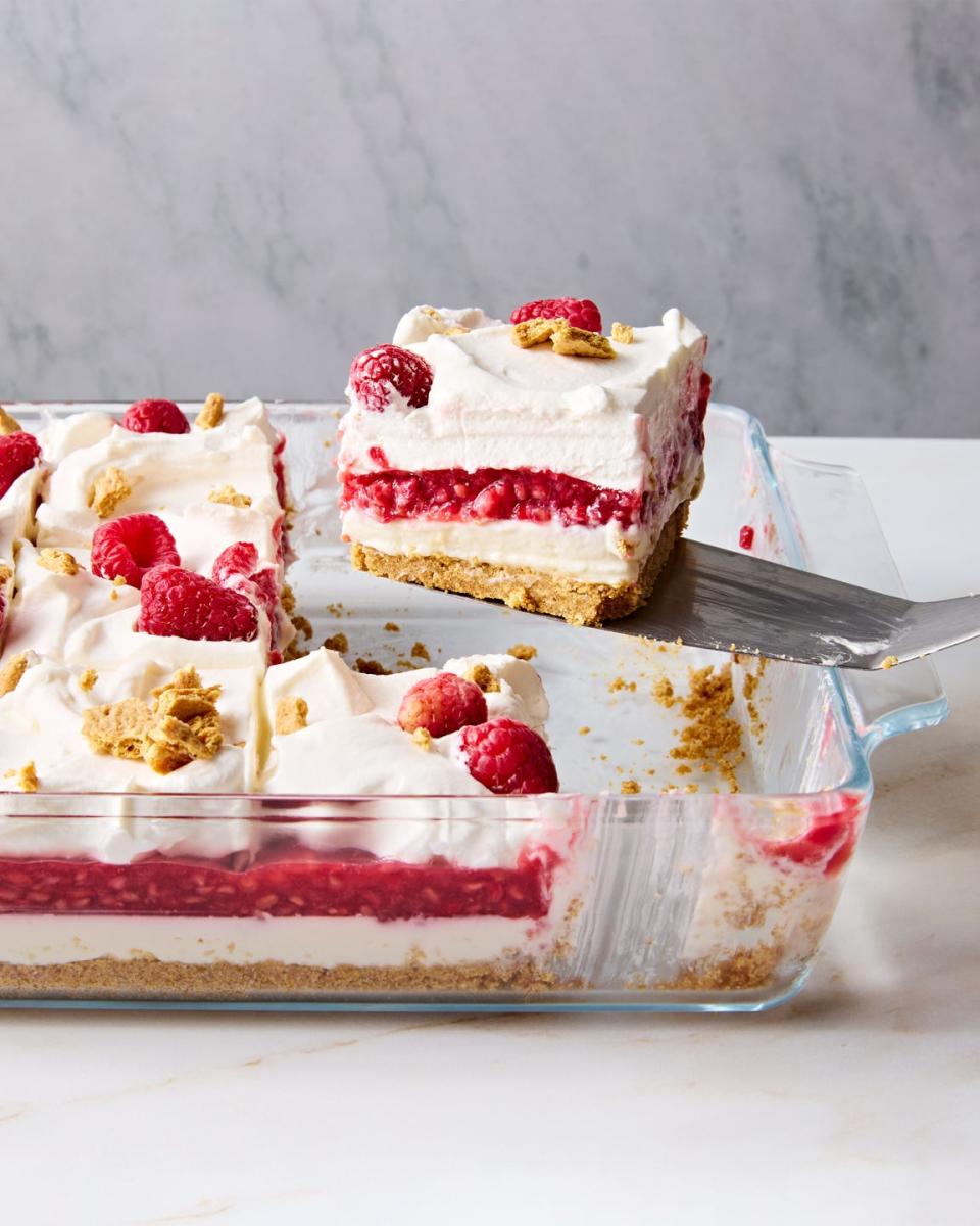 a slice of raspberry cheesecake lasagna lifting out a glass baking dish