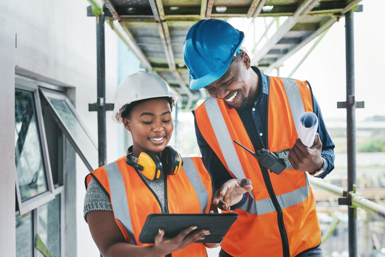 Construction workers working on a project plan wearing hardhats.