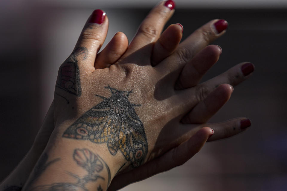 A woman uses anti-bacterial gel while waiting in line for her third shot of a COVID-19 vaccine, at the start of a booster shot campaign where people can get even a fourth shot in Santiago, Chile, Monday, Jan. 10, 2022. (AP Photo/Esteban Felix)