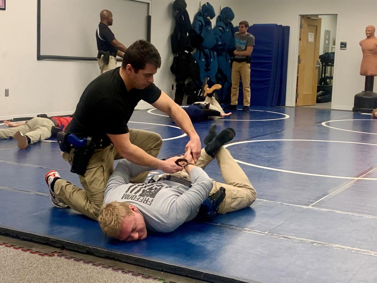 Canton city police cadet Brandon Robb practices handcuffing with Canton cadet Ty Cowling in a facedown position during the Stark State College law enforcement academy in Jackson Township.