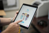 An employee of Hazel Health displays the opening page of the company's app, which allows Miami-Dade County public school students to receive telehealth therapy services, on World Mental Health Day, Tuesday, Oct. 10, 2023, at Miami Arts Studio, a public 6th-12th grade magnet school, in Miami. (AP Photo/Rebecca Blackwell)