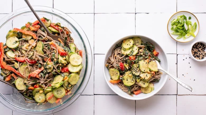 Soba noodle salad on white tile background