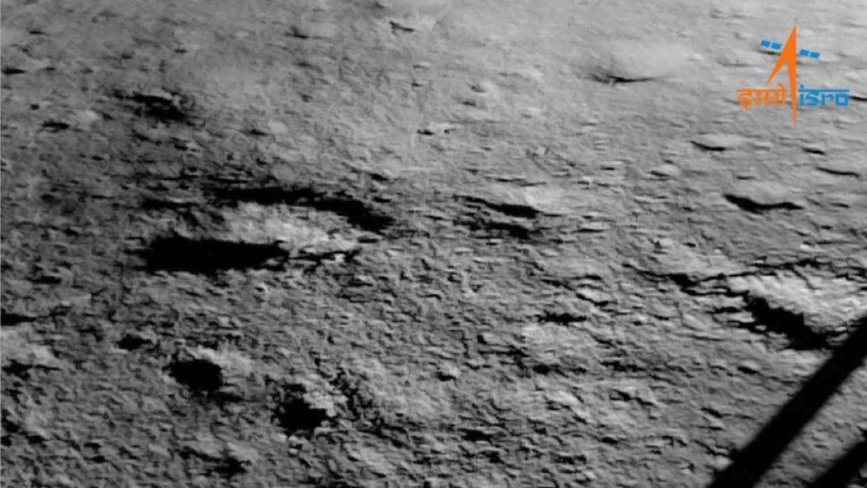  The gray surface of the moon can be seen beside the leg of a lunar lander. 