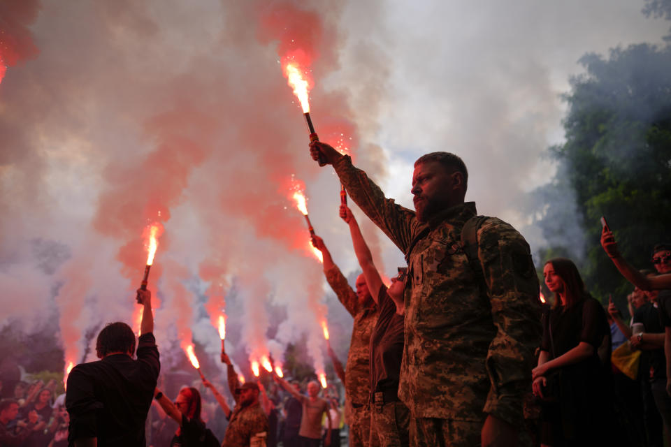 Soldiers hold flares as they attend the funeral of activist and soldier Roman Ratushnyi in Kyiv, Ukraine, Saturday, June 18, 2022. Ratushnyi died in a battle near Izyum, where Russian and Ukrainian troops are fighting for control of the area. (AP Photo/Natacha Pisarenko)