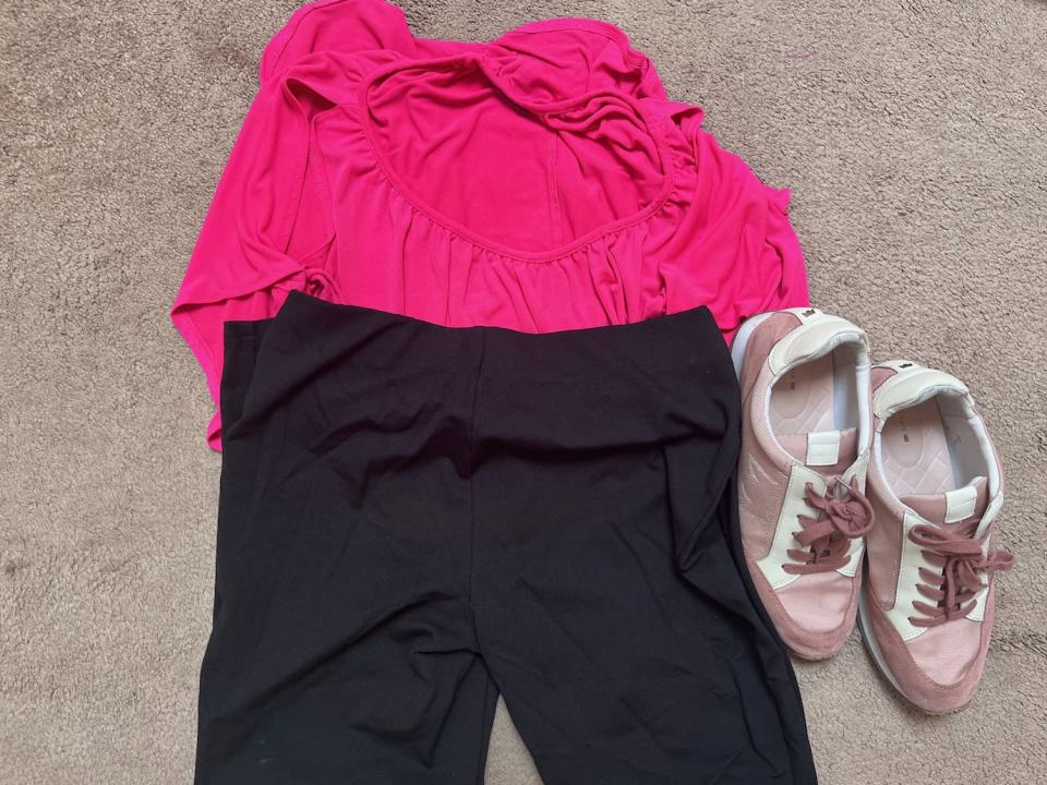 pink shirt, black leggings, and dusty pink sneakers on the floor