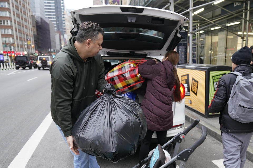 Mayra Martinez, right, of Colombia, and her partner pack their belongings into a car after leaving the Row Hotel , Tuesday, Jan. 9, 2024, in New York. (AP Photo/Mary Altaffer)