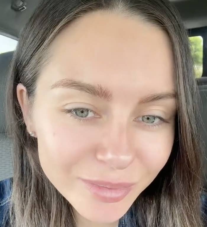 Close-up of a woman smiling lightly at the camera from inside a vehicle