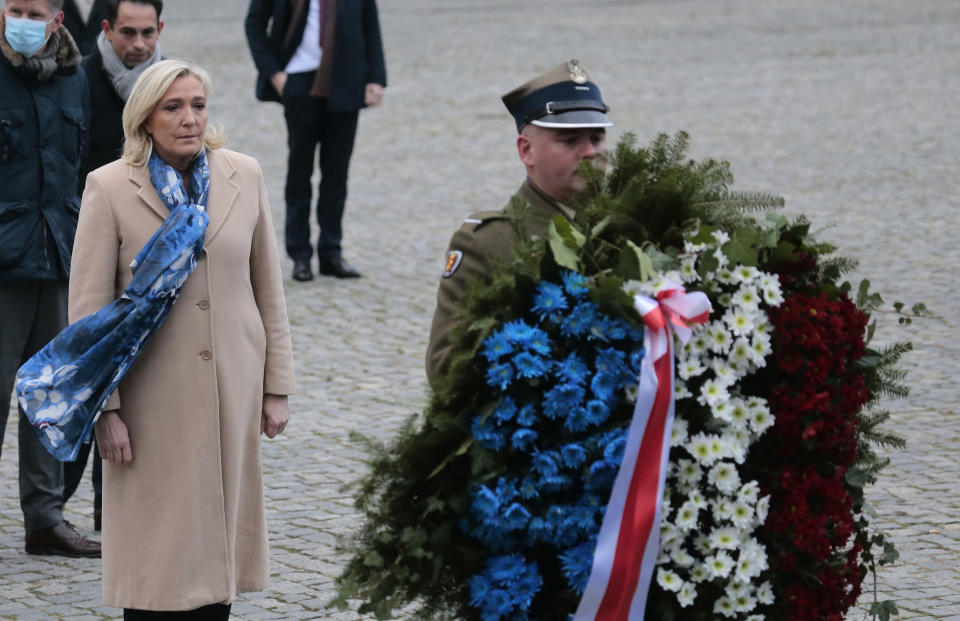 French far-right leader Marine Le Pen, left, pays respects at the memorial to the heroes of the Warsaw Ghetto uprising, in Warsaw, Poland, Friday Dec. 3, 2021. The memorial honors Jews who rose up against Nazi German forces during World War II. Le Pen is in Warsaw to attend a meeting of the leaders of right-wing and far-right parties on Saturday. (AP Photo/Adam Jankowski)
