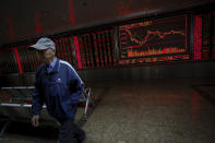 An investor walks by an electronic screen displaying stock prices at a brokerage house in Beijing, Wednesday, Oct. 23, 2019. Asian stock markets followed Wall Street lower Wednesday after major companies reported mixed earnings and an EU leader said he would recommend the trade bloc allow Britain to delay its departure. (AP Photo/Andy Wong)