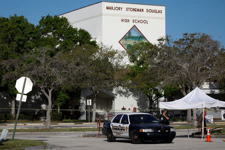 FILE PHOTO: A police officer Jamie Rubenstein stands guard in front of the Marjory Stoneman Douglas High School, after the police security perimeter was removed, following a mass shooting in Parkland, Florida, U.S., February 18, 2018. REUTERS/Carlos Garcia Rawlins/File Photo