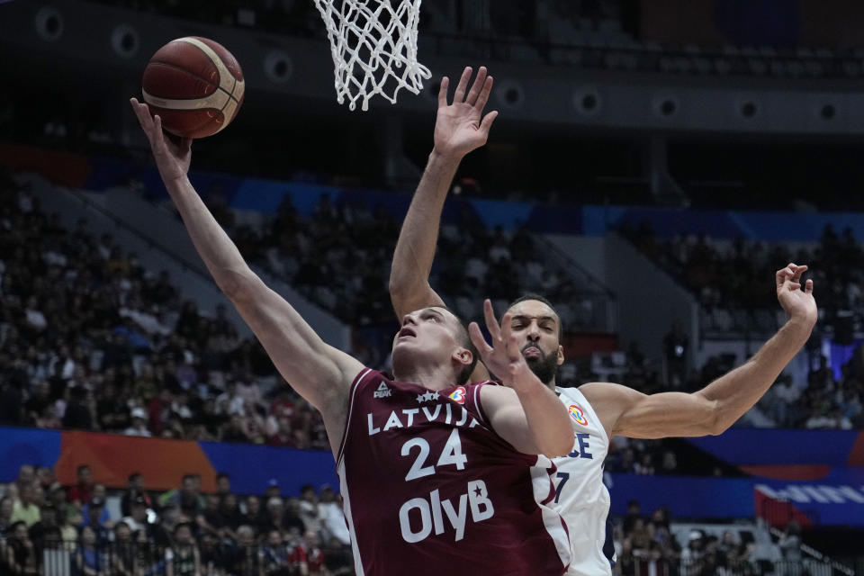 Latvia forward Andrejs Grazulis (24) shoots against France center Rudy Gobert (27) during the Basketball World Cup group H match between France and Latvia at the Indonesia Arena stadium in Jakarta, Indonesia, Sunday, Aug. 27, 2023. (AP Photo/Achmad Ibrahim)