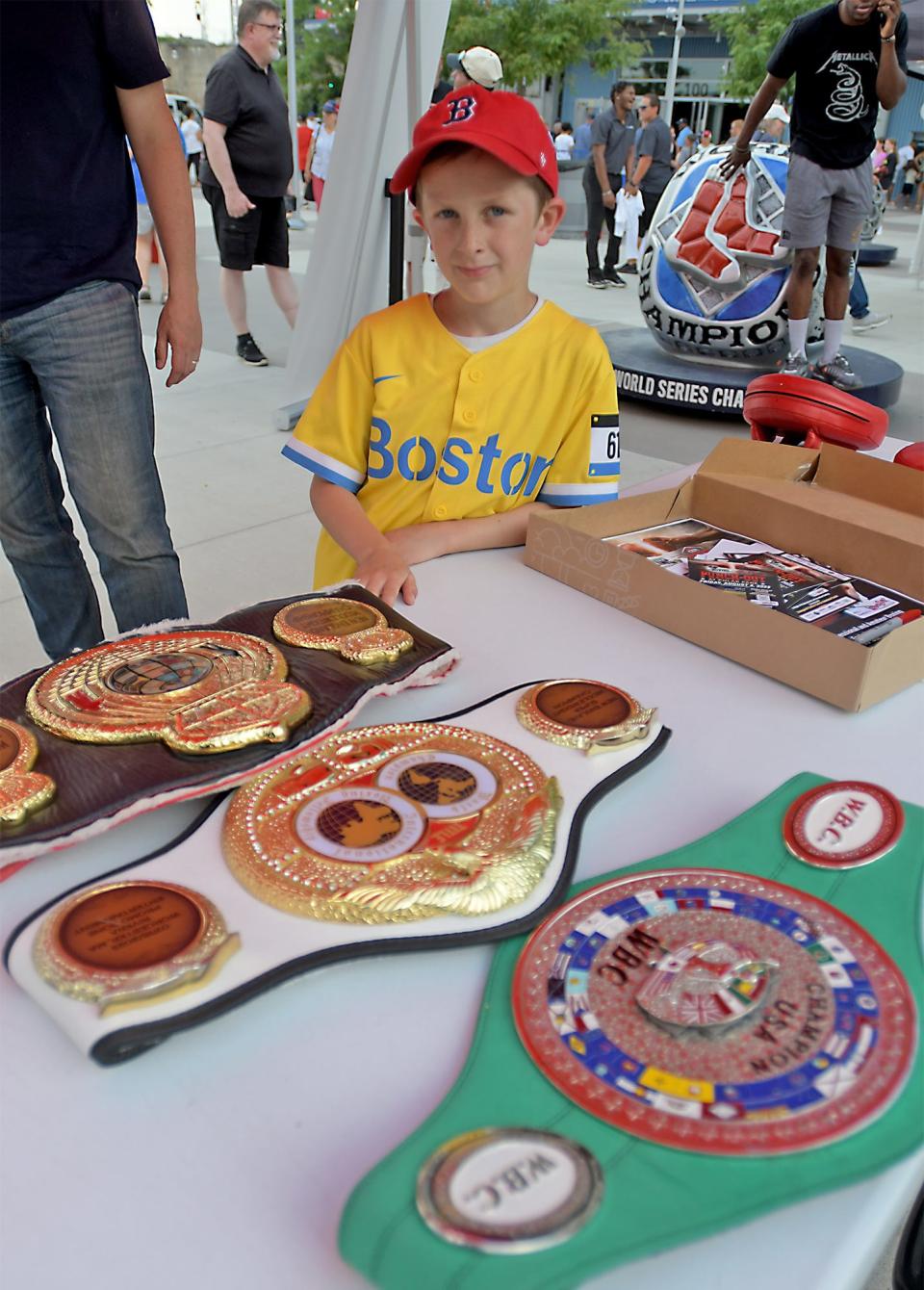 Mitchell Geher, 7, of West Newton, admires the three championship belts held by Worcester's Kendrick Ball Jr. while watching boxers working out last week in front of Polar Park.