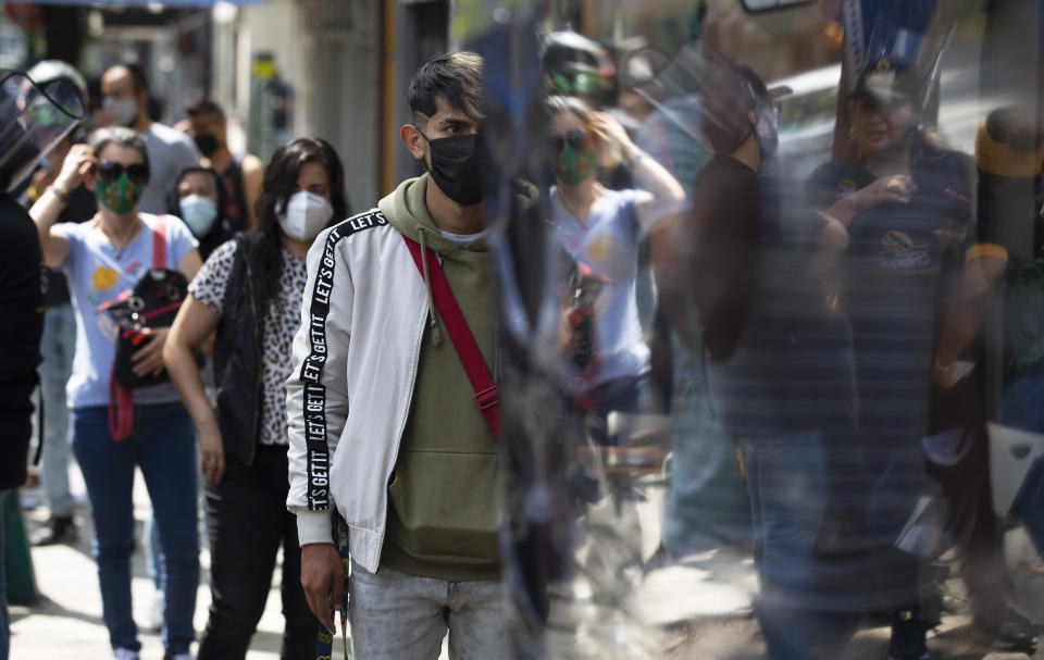 Customers, wearing protective face masks amid the new coronavirus pandemic, stand in line at a stall selling "torta de chilaquiles", in Mexico City, Saturday, Aug. 1, 2020. Mexico has imposed a very lax and partial lockdown of economic activity that has not stopped high levels of contagion, but has strangled the economy. (AP Photo/Marco Ugarte)