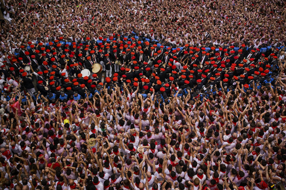 Revellers raise their arms as a music band plays in the town hall square after the 'Chupinazo' rocket, to mark the official opening of the 2023 San Fermín fiestas in Pamplona, Spain, Thursday, July 6, 2023. (AP Photo/Alvaro Barrientos)