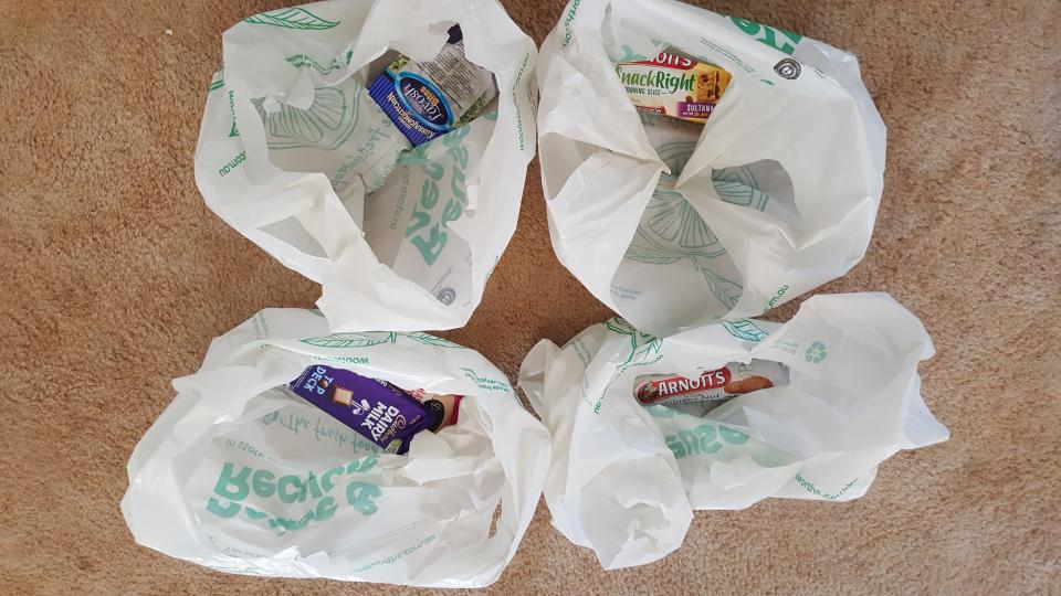 Photo shows four Woolworths plastic shopping bags with single items inside. 