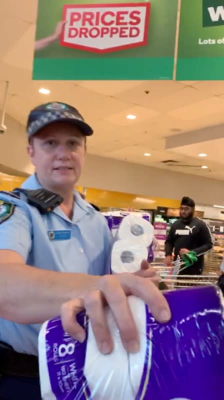 Police officers distribute toilet papers and paper towels to the customers at Woolworths supermarket, in Prospect