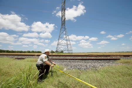 Caldwell County Sheriff's Deputy Sean Quinn rolls out crime scene tape to secure the area of a hot air balloon crash in Maxwell, Texas, U.S. July 30, 2016. Ralph Barrera/Austin American-Statesman/via REUTERS