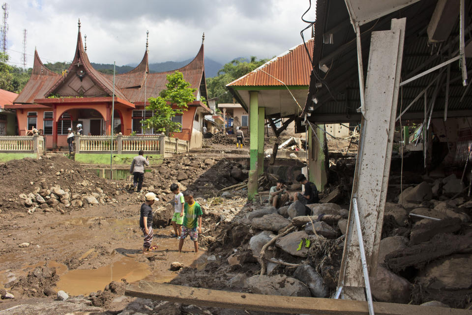 People inspect buildings damaged by a flash flood in Agam, West Sumatra, Indonesia, Monday, May 13, 2024. Rescuers recovered more bodies Monday after monsoon rains triggered flash floods on Indonesia's Sumatra Island, bringing down torrents of cold lava and mud, leaving a number of people killed and missing. (AP Photo/Fachri Hamzah)