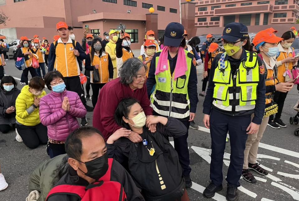 白沙屯媽祖昨日上午從清水起駕，一名阿嬤無法跪拜，二名女警扶持協助鑽轎底。（記者陳金龍攝）