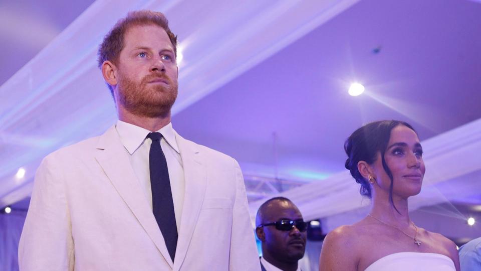 Prince Harry and Meghan Markle stand watching a performance